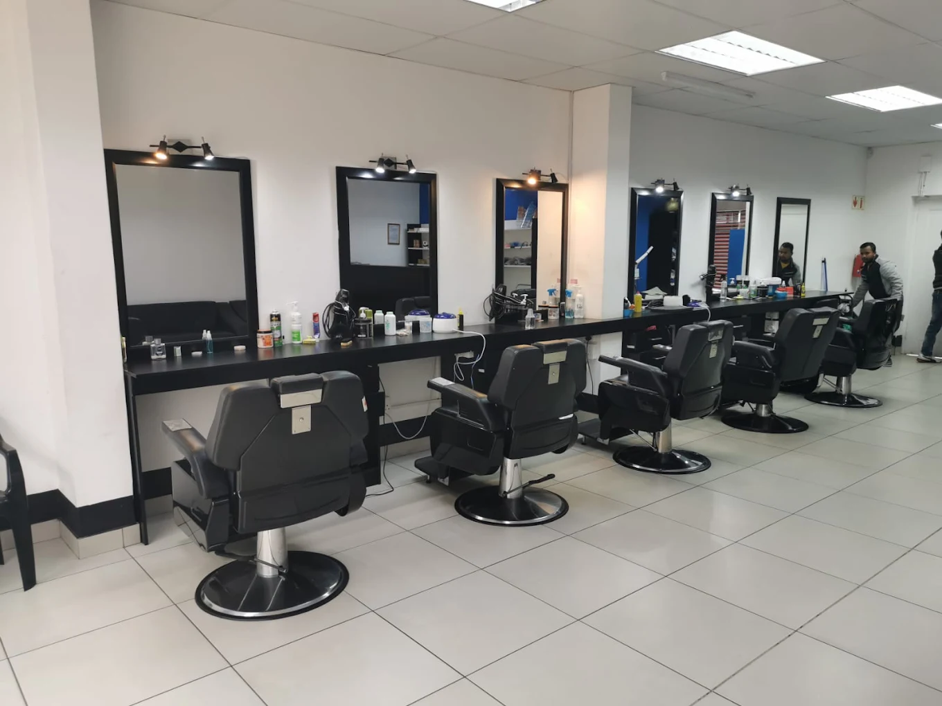 A row of black barber chairs facing lit mirrors inside Mohammed's Barber Shop