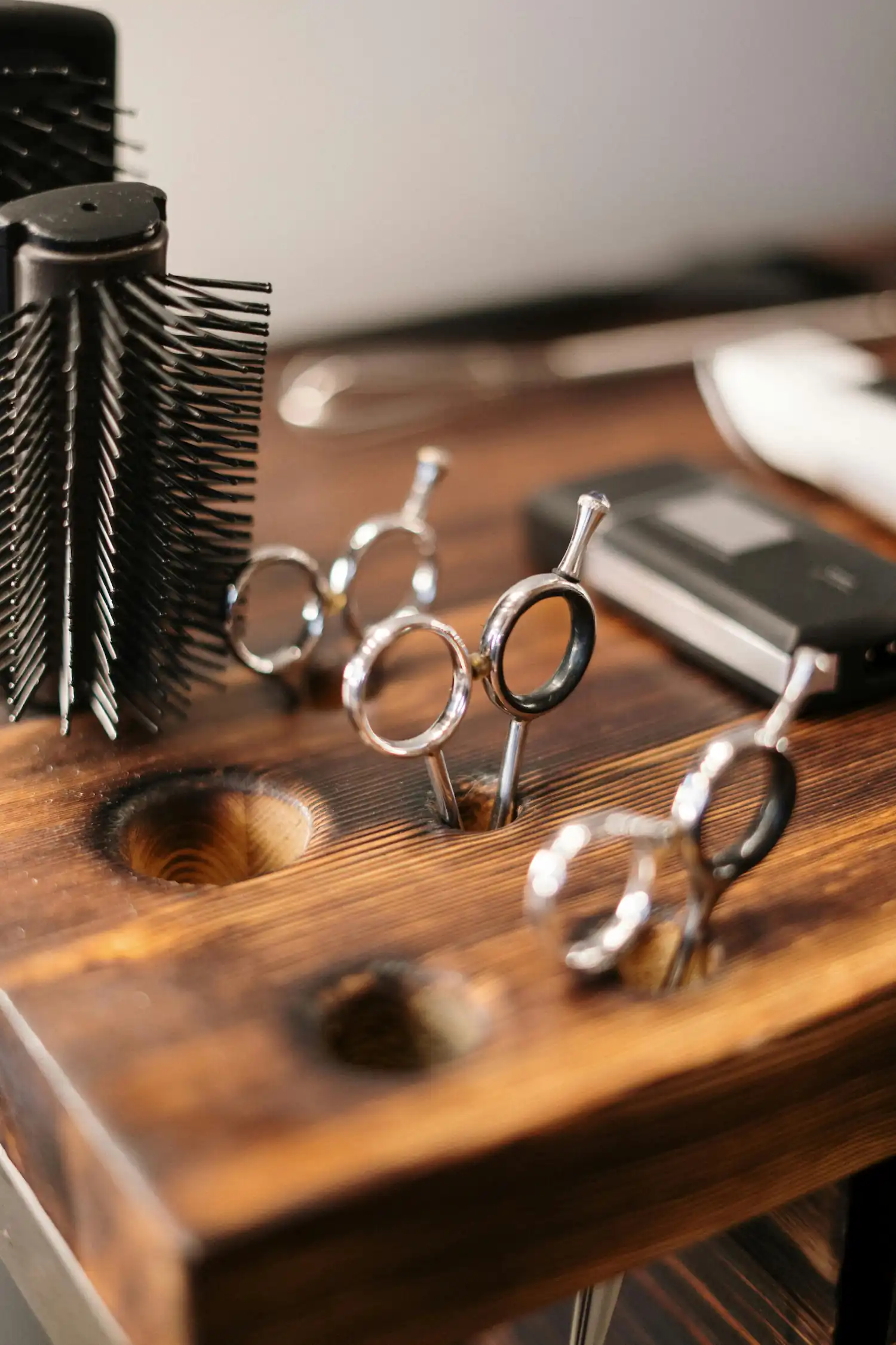 Scissors standing in a wooden holder next to a round brush