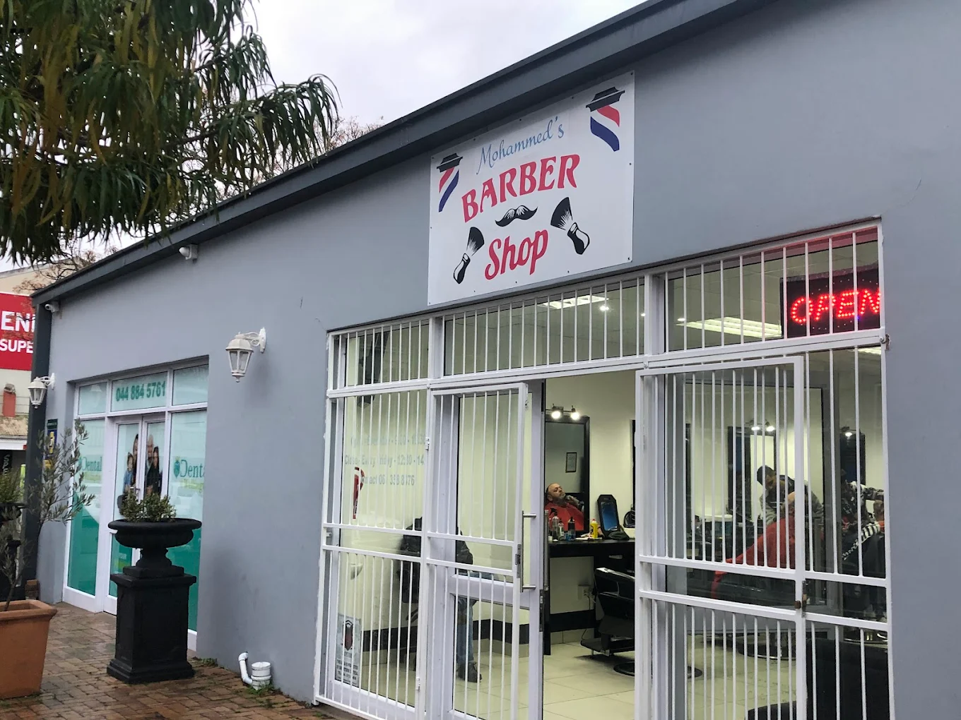 Shopfront of Mohammed's Barber Shop with the OPEN sign lit